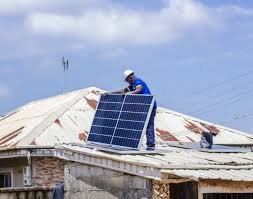 A young Nigerian solar technician installing rooftop panels under bright sunlight in Abuja. Image Description