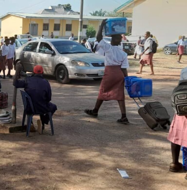 Parents evacuating students with luggage at FGGC Bwari after school closure.