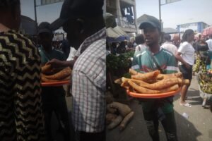 Ayuba holds cow skin, known as ponmo at Kubwa Centre Market as customers queue for affordable protein alternatives.