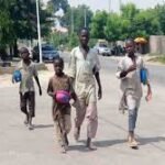 Out-of-school children sitting along a street in Northern Nigeria, highlighting the country’s education crisis.