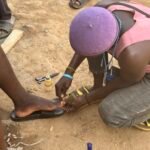 Roadside pedicurist providing foot grooming service in Katampe, Abuja.