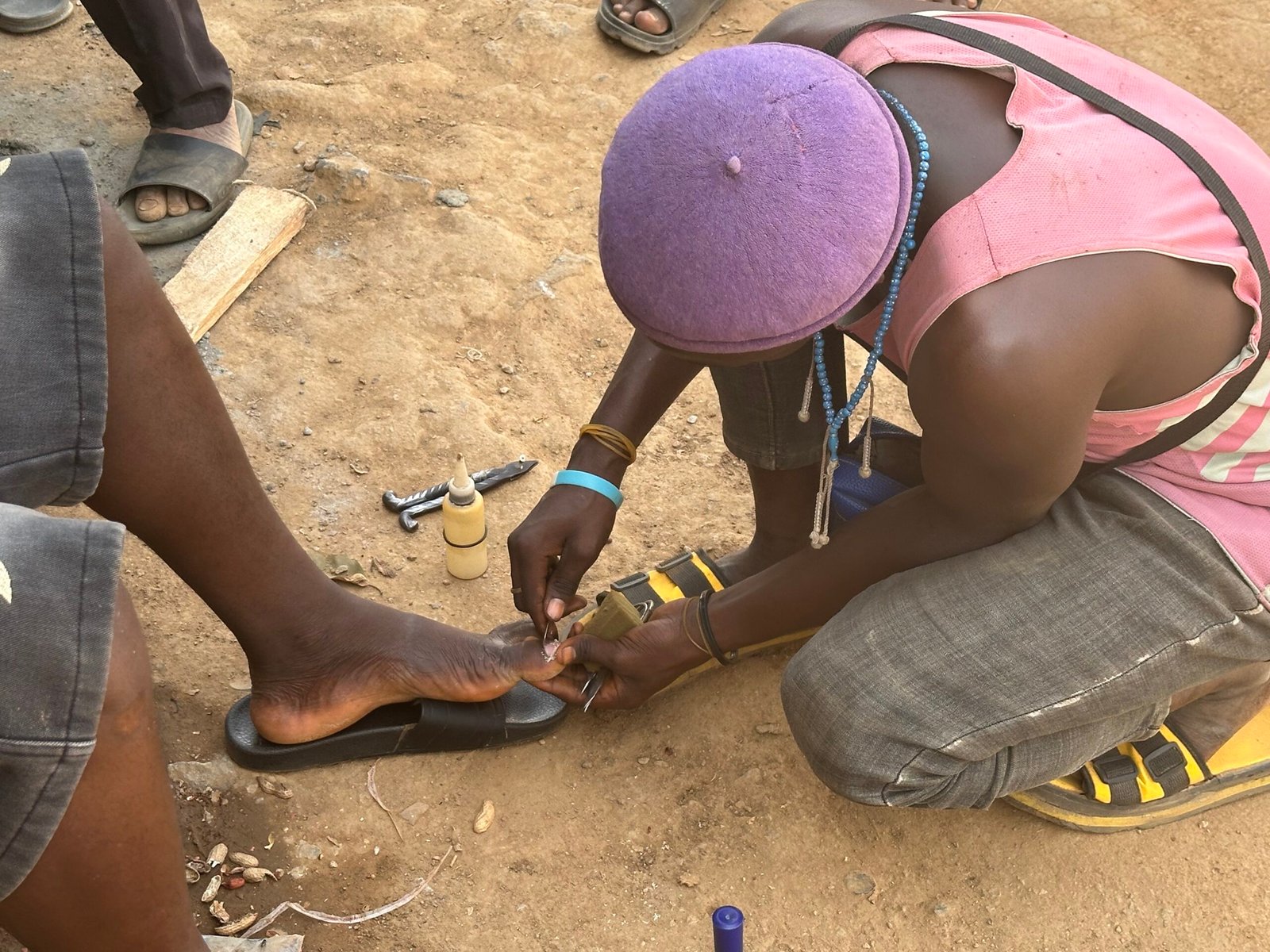 Roadside pedicurist providing foot grooming service in Katampe, Abuja.