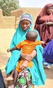 Teenage mother holding child in Kano community