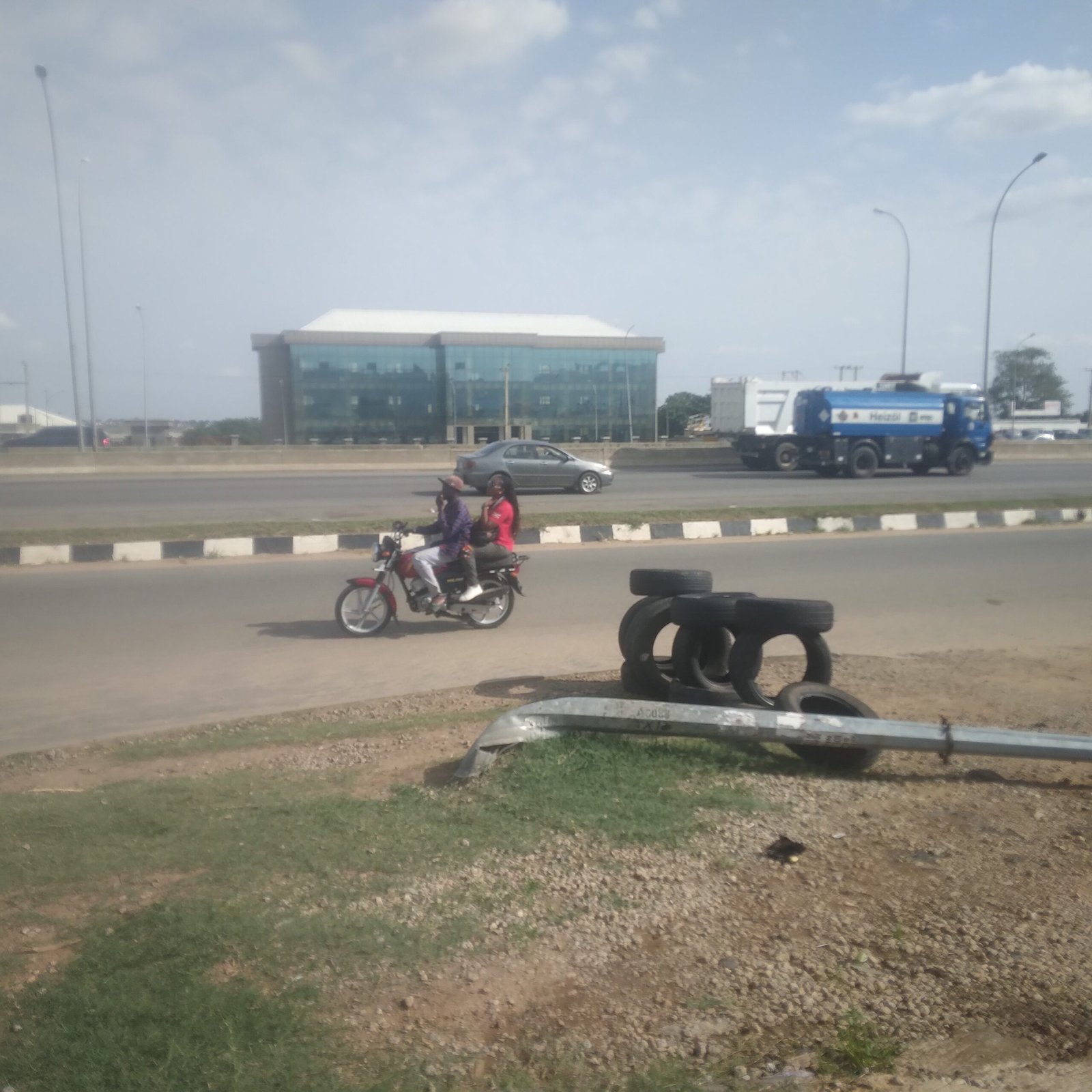 Commercial motorcycle rider driving against traffic on a busy Abuja road.