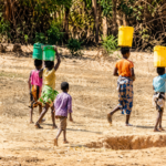 Children carrying jerrycans while searching for water before school in Kano.