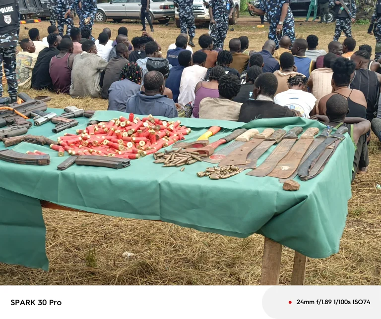 Police officers display recovered weapons and suspects during Operation Kosaye.