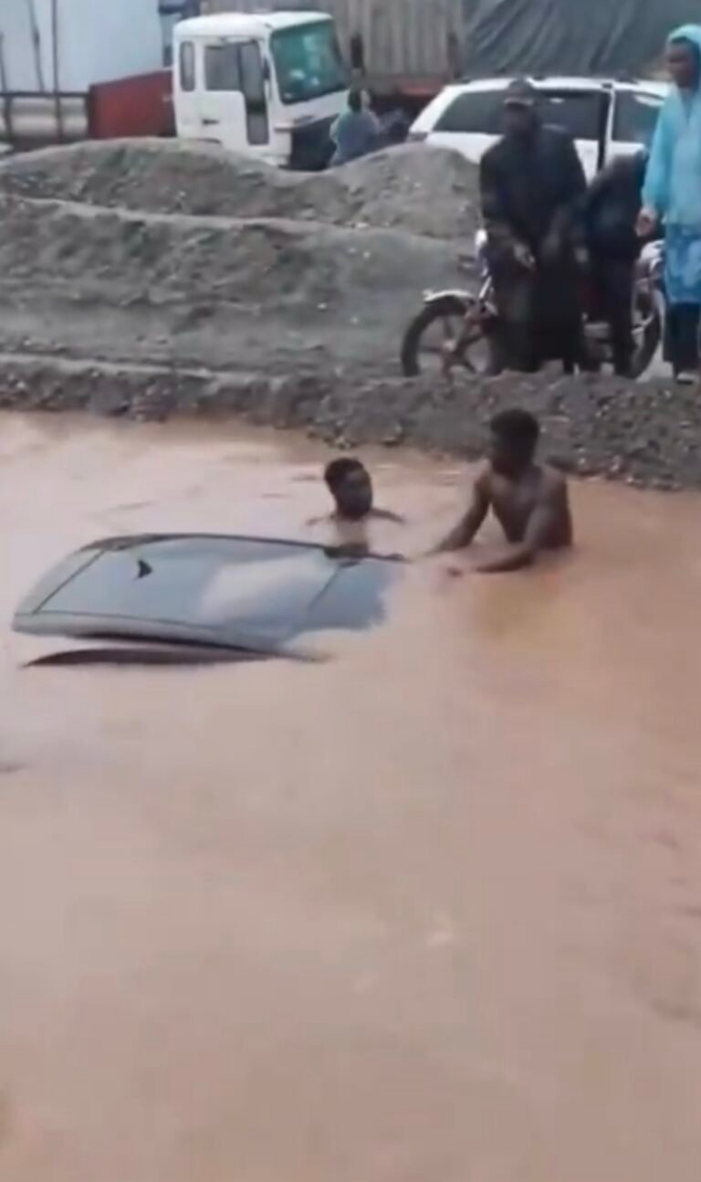 A vehicle submerged in floodwater on the Benin-Warri Expressway as rescuers attempt to assist occupants.